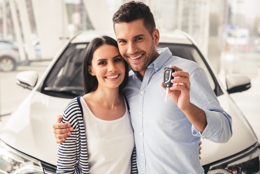 husband and wife holding a key of new car